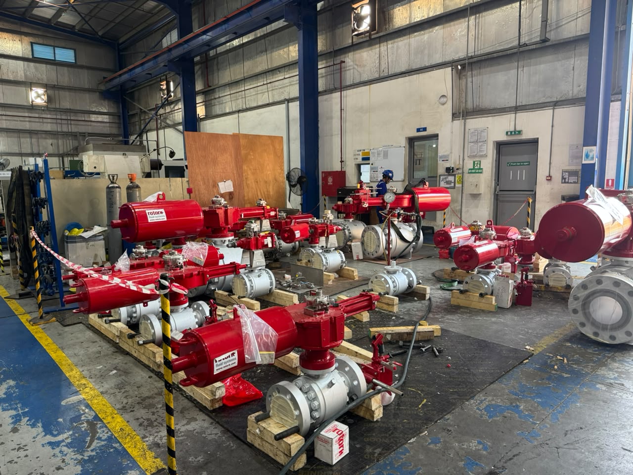 Rows of ball valves fitted with red pneumatic actuators, mounted on timber pallets